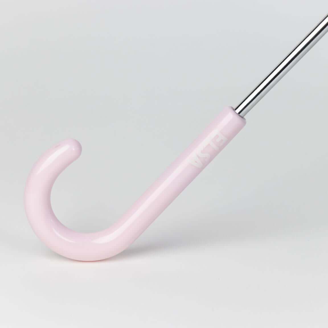 Light pink umbrella handle with a silver pole against a neutral background