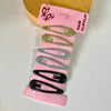 Alt Tag: Hárspennur - Glimmer 6 stk on a display board, featuring glittery hair clips in gold, silver, and black colors.