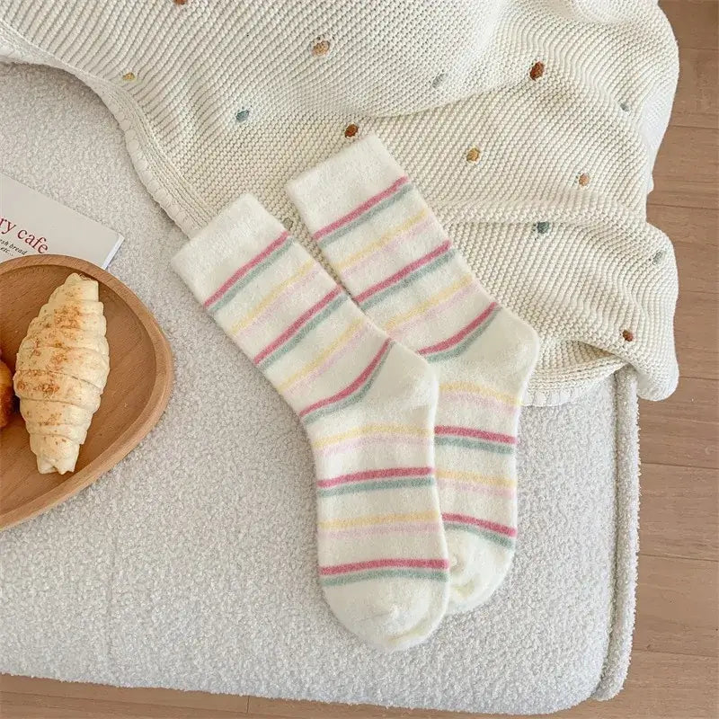 Kósýsokkar - hvítir og bleikir. Soft plush socks on a cozy blanket, featuring pink and white stripes, perfect for winter warmth.